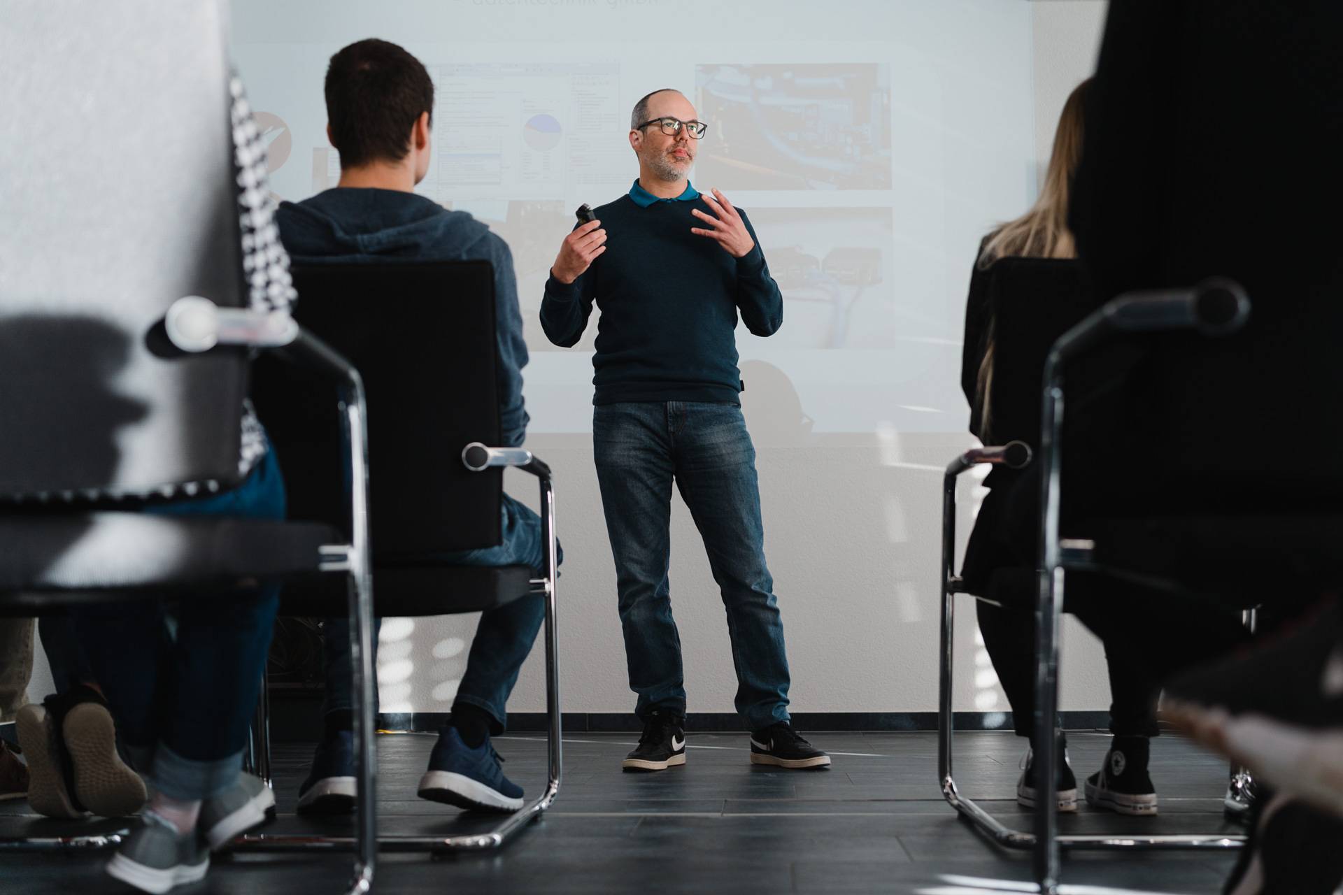 Mann hält eine Schulung vor Teilnehmenden und erläutert Inhalte anhand einer Präsentation