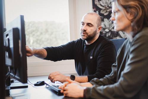 Support-Mitarbeiter erklärt einer Kollegin Inhalte auf dem Monitor