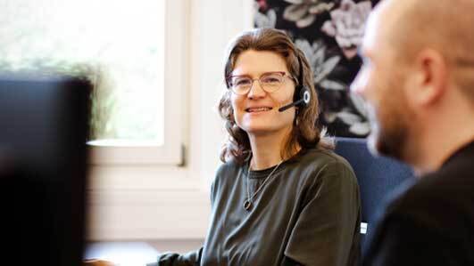 Frau mit Headset schaut in die Kamera